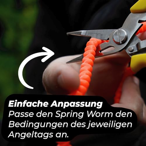 Nahaufnahme eines leuchtenden orangefarbenen Trout Master Spring Worms, der in einer Hand gehalten wird, ideal für das Forellenangeln, mit Fokus auf die anpassbare Länge und lebensechte Präsentation.