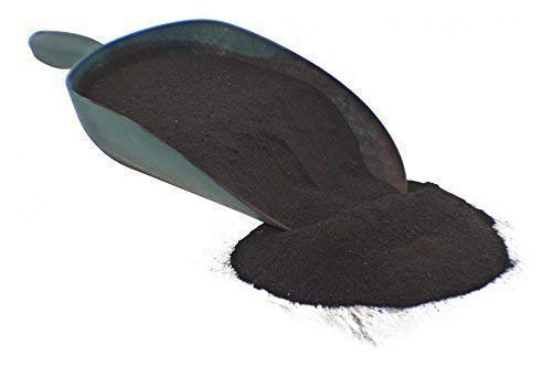 Schaufel mit dunklem, pulverförmigem Blutmehl für Haustiere auf flacher Oberfläche